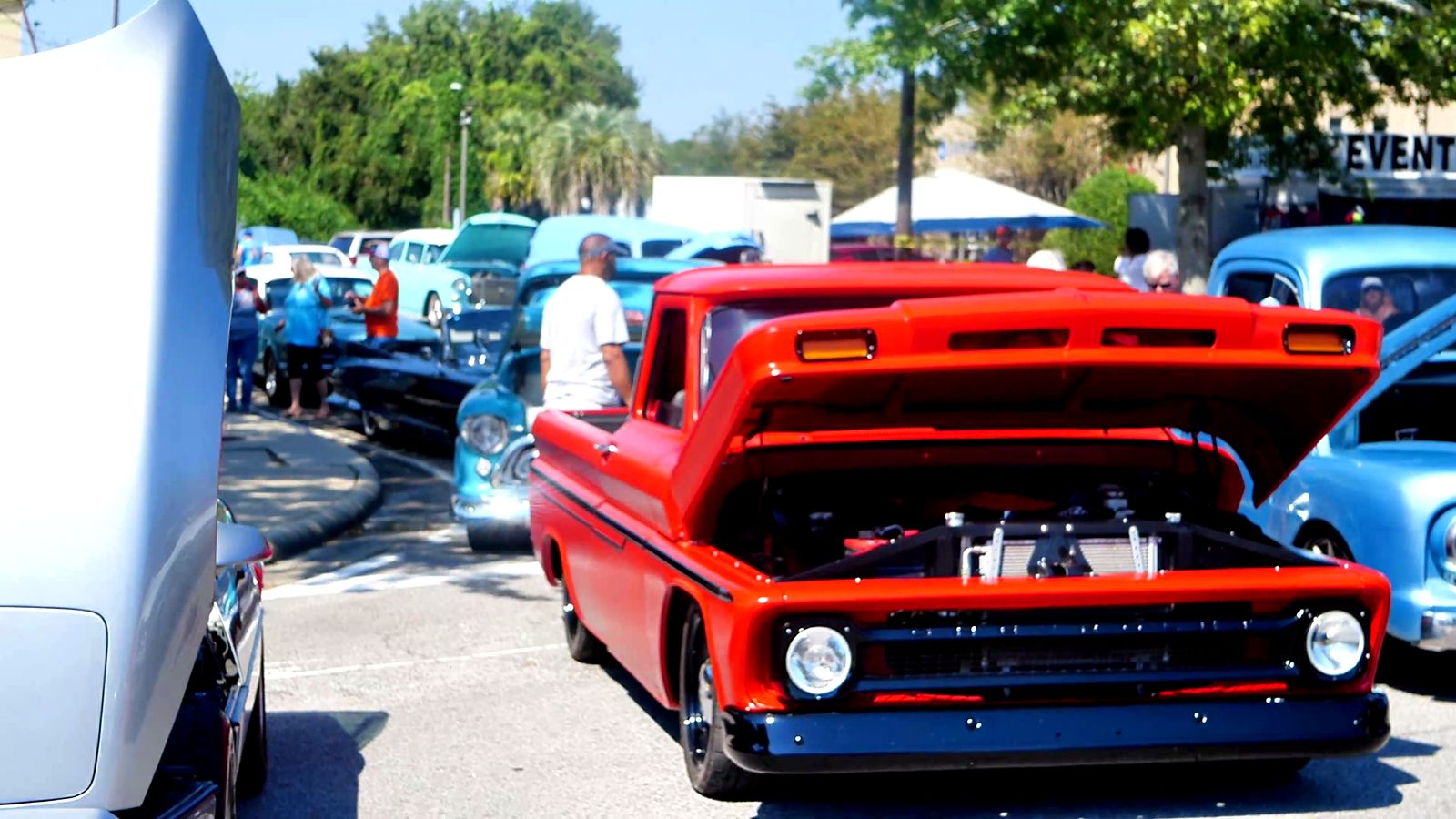 A bright red vintage pickup with its hood up