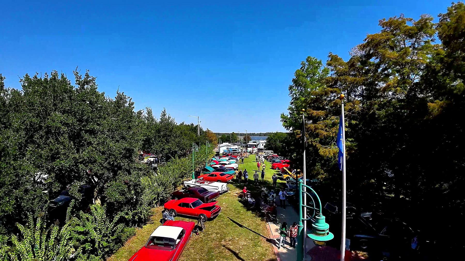 Classic cars parked along the riverfront green at Cruisin' the River City, seen from the air