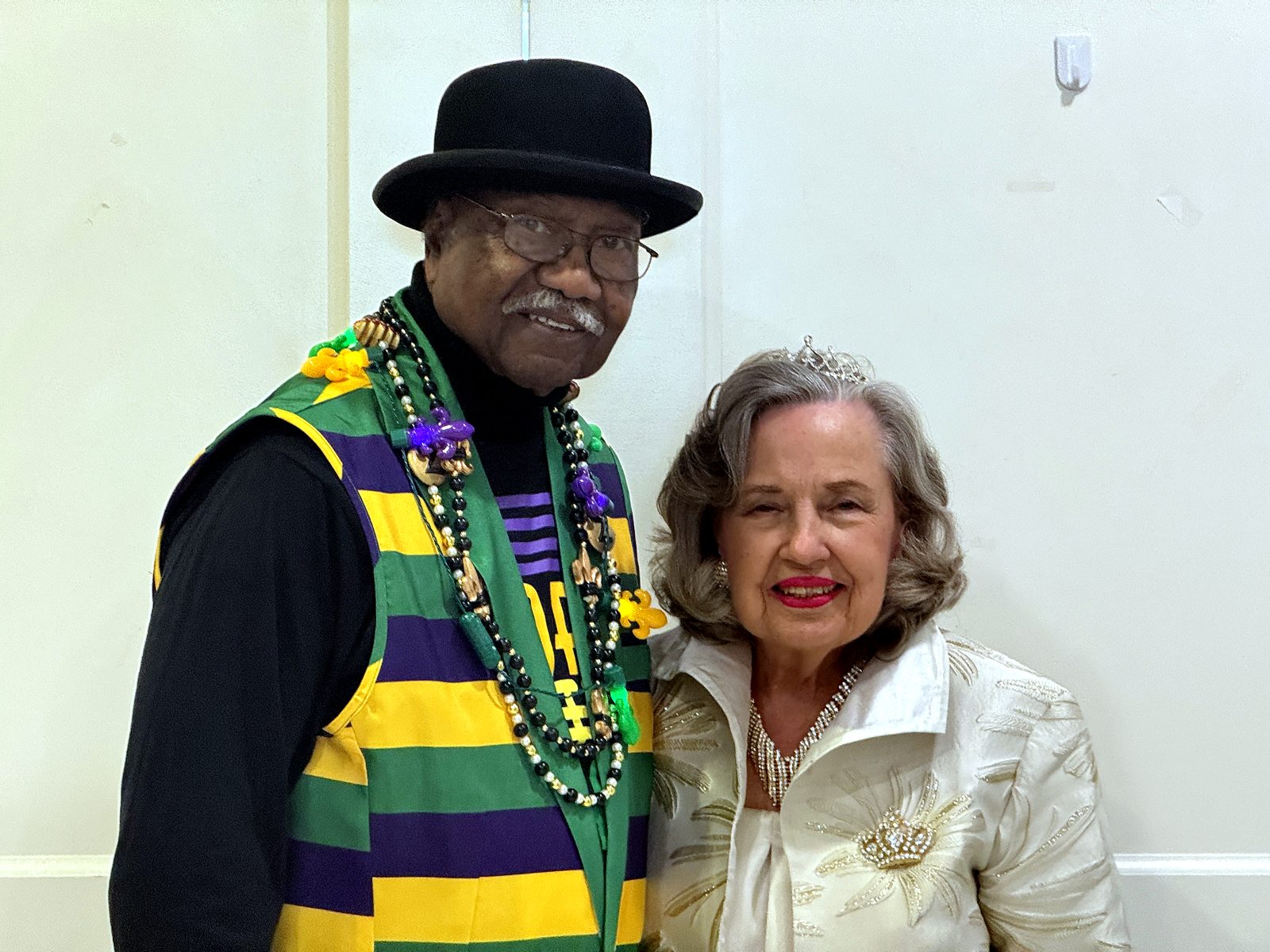 A couple in purple, green, and gold Mardi Gras beads