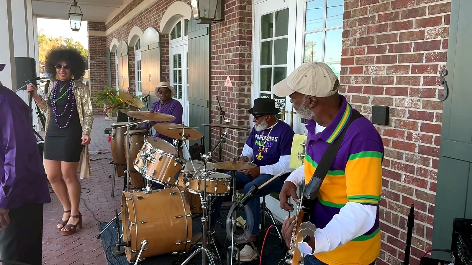 A drummer in Mardi Gras colors playing outside on the route