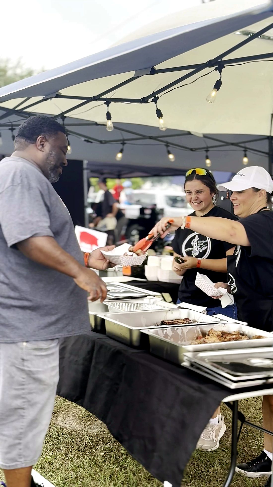A team serving plates under the string lights of their booth