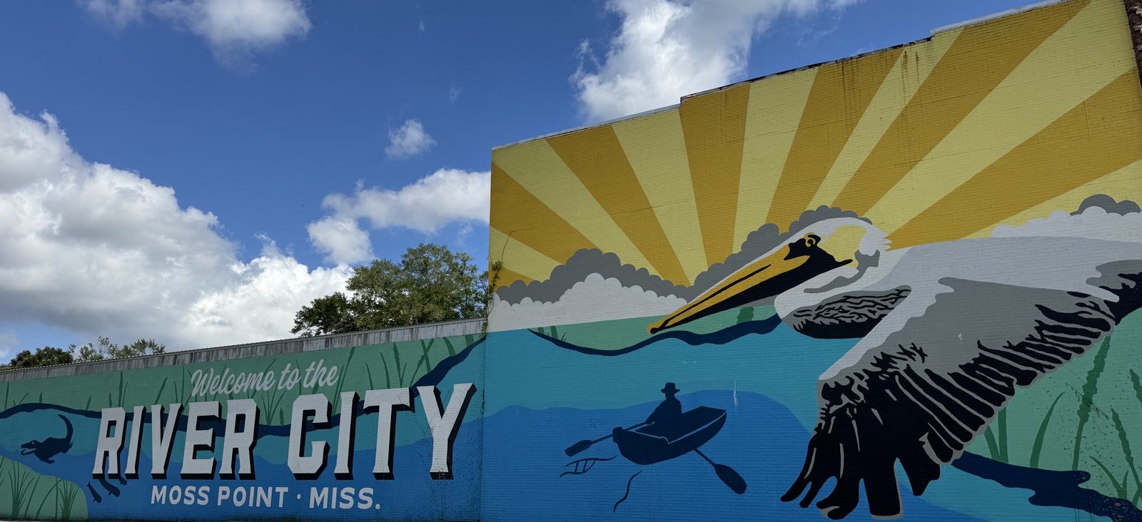 The River City mural in downtown Moss Point, reading Welcome to the River City, Moss Point, Miss., with a brown pelican in flight