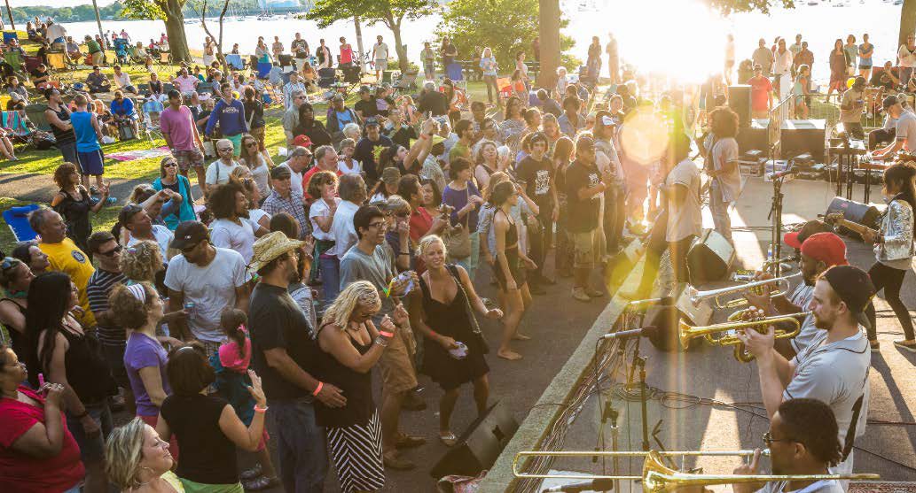 A crowd dancing at a Levitt AMP concert on the Moss Point riverfront at golden hour